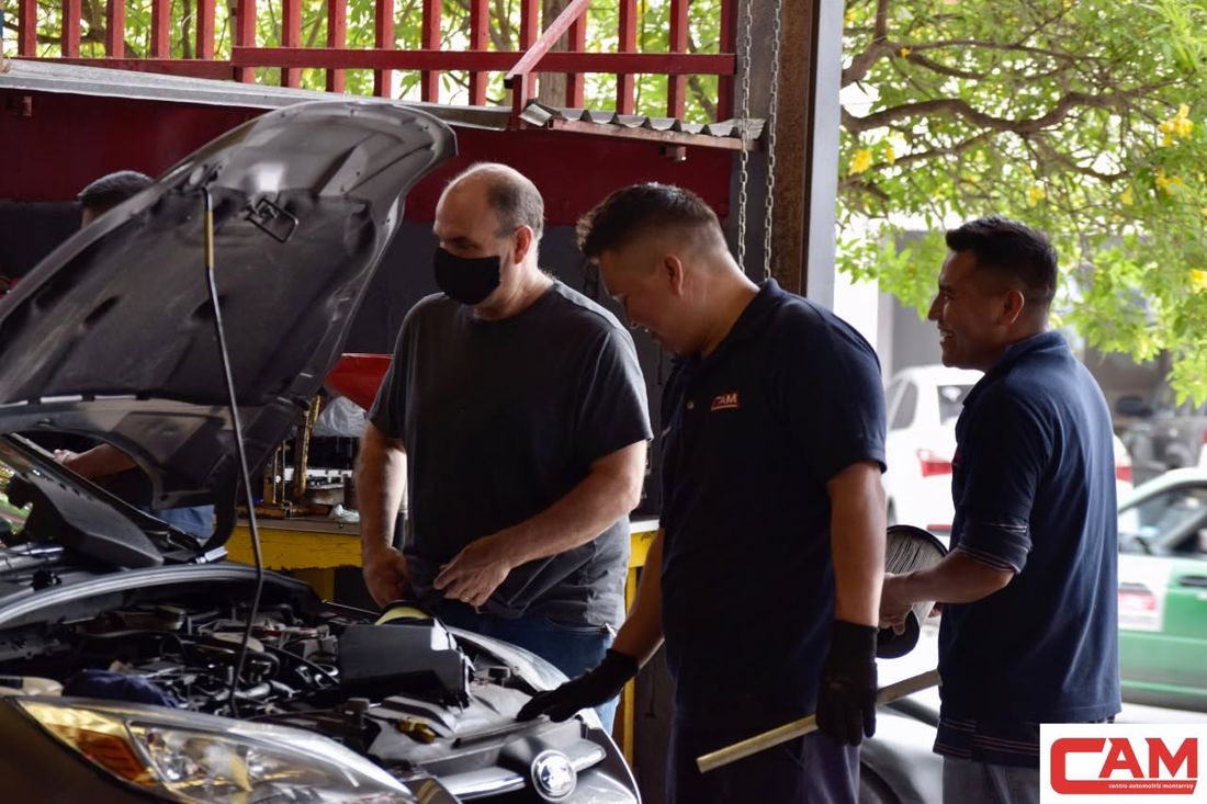 Mecánicos de CAM revisando un motor junto con un cliente